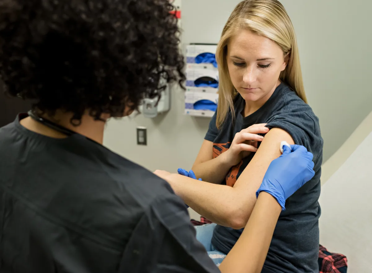 An enlarged image of a vybe urgent care doctor preparing a patient to receive a shot.