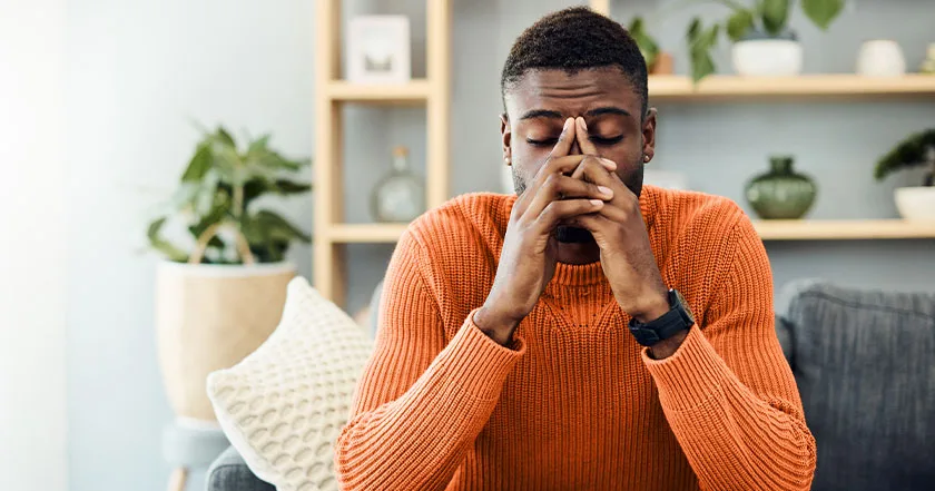 An enlarged image of a future vybe urgent care male patient sitting on a couch shows signs of stress and mental fatigue.