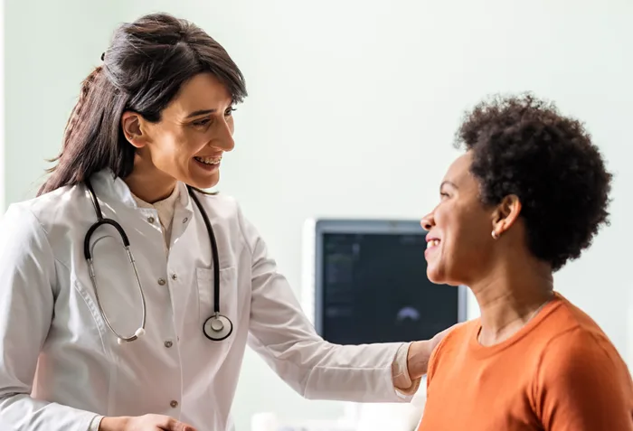 A vybe urgent care doctor comforting a female patient with a smile.