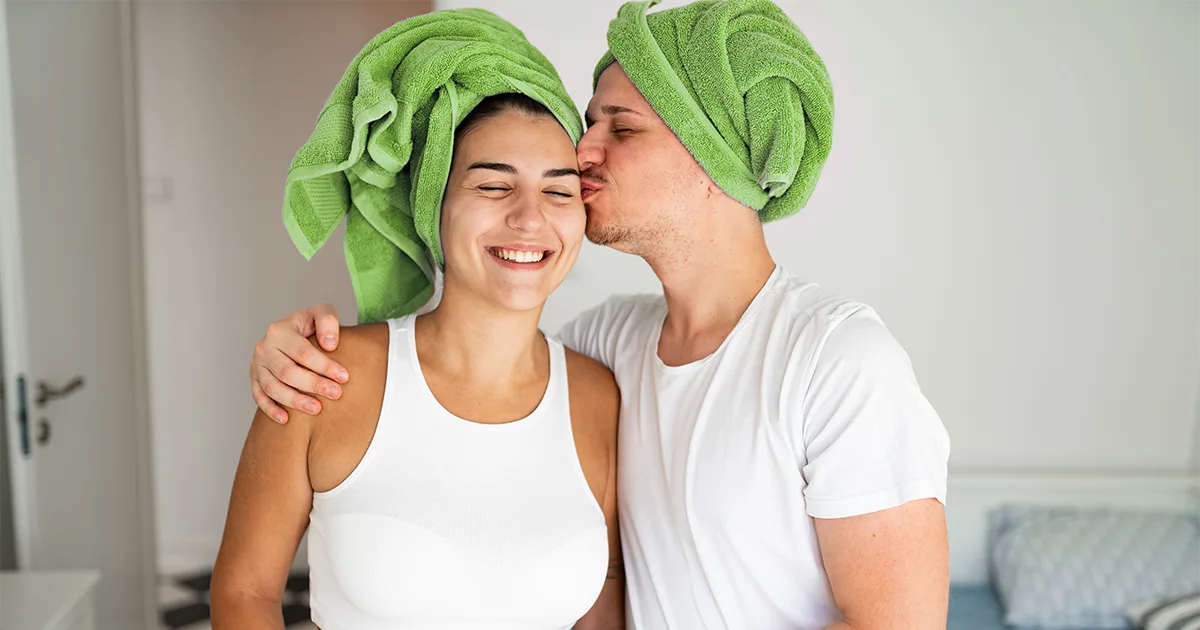An enlarged image of a man kissing his girlfriend on the cheek after they've both taken a shower.