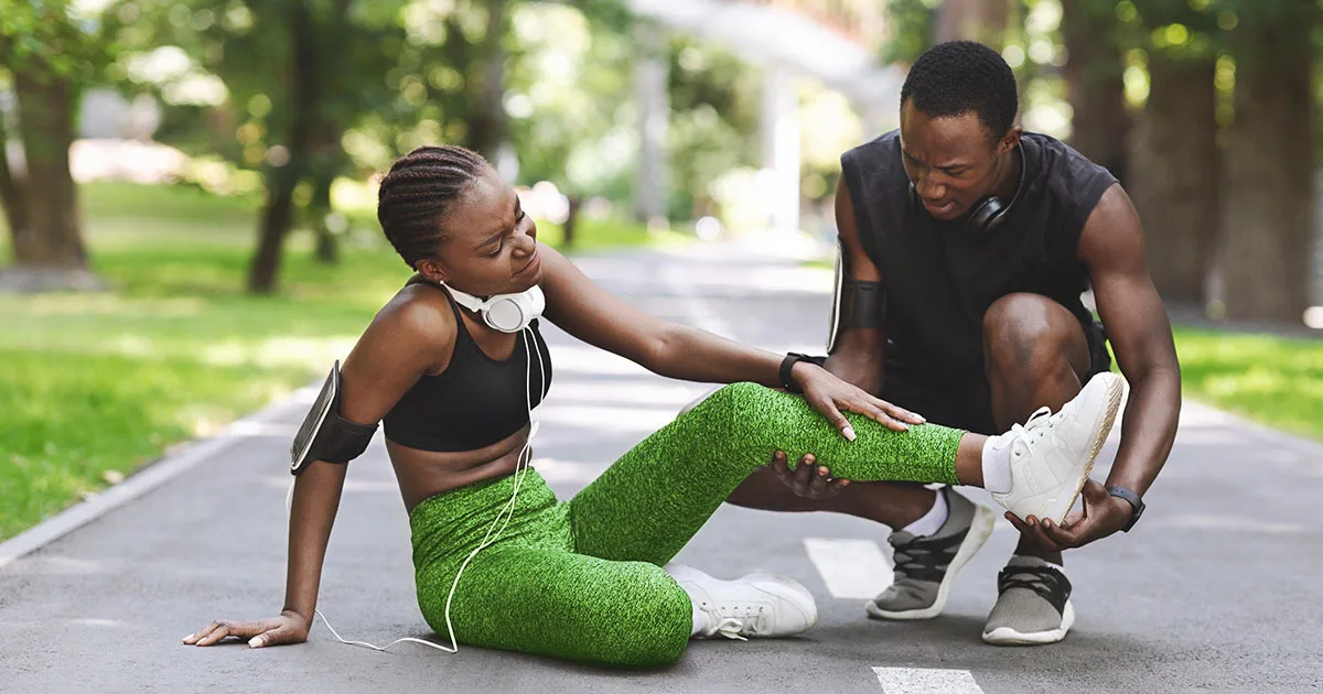 An enlarged image of a man checking on a woman who has suffered a leg injury while jogging.