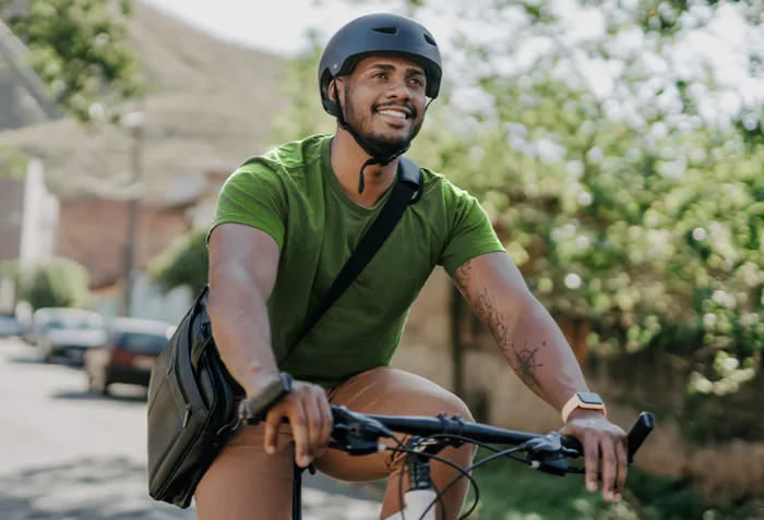 An enlarged image of a vybe urgent care male patient smiling while riding his bike outdoors.
