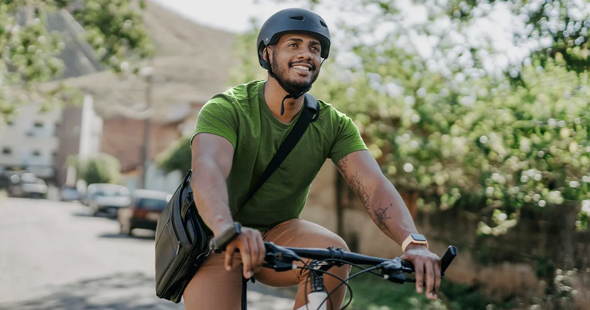 An enlarged image of a vybe urgent care male patient smiling while riding his bike outdoors.