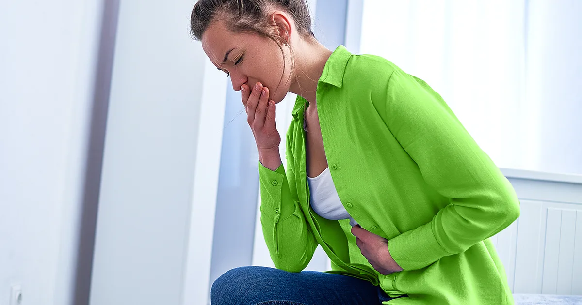 An enlarged image of a future vybe urgent care patient holding her stomach in pain due to having the summer flu.