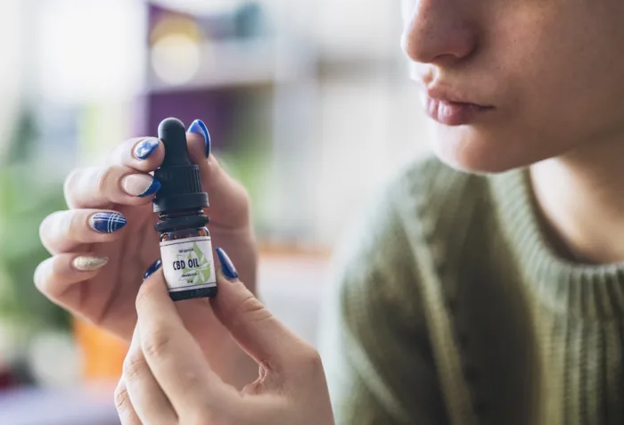 An enlarged image of a woman holding a bottle of cbd oil.