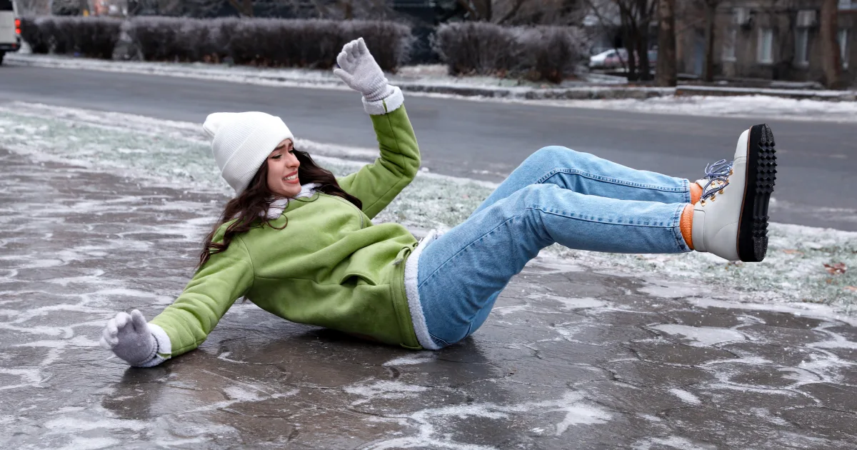 Young women in a jacket and winter gear has had a winter accident and slipped on ice landing on her back.